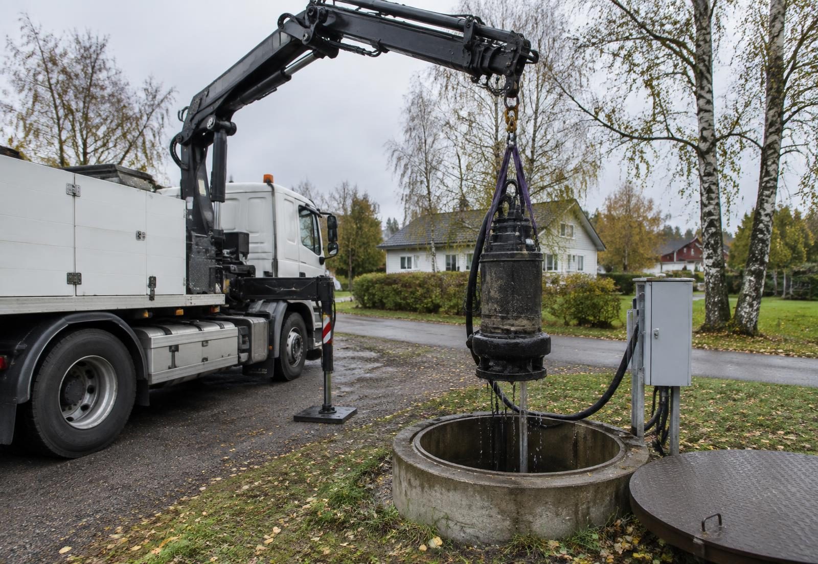 Kranbil lyfter en dränkbar avloppspump ur en pumpbrunn